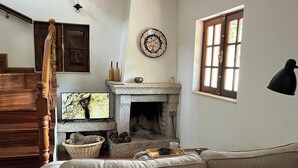 Ein gemütliches Wohnzimmer mit Kamin, einer Holztreppe, einem Sofa und einem Fenster mit Blick.