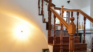 Eine Holztreppe mit Handlauf, eine Steinmauer und ein Regal mit Teekanne und einer Schachtel.