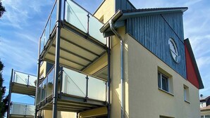 Ein modernes, zweistöckiges Haus mit flachem Dach, großen Fenstern und einem Balkon.