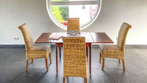 Ein Essbereich mit rundem Fenster, dunklem Fliesenboden und Korbstühlen.