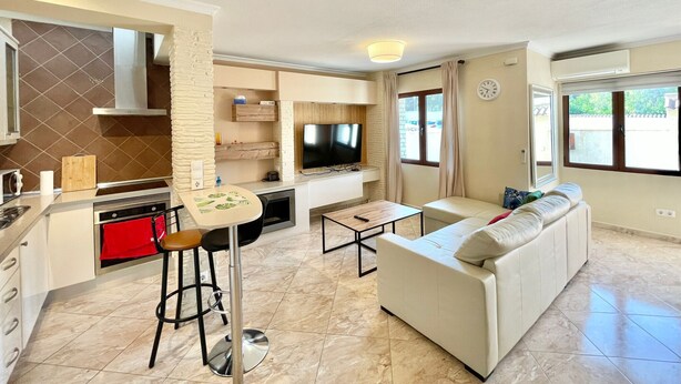 Een moderne woonkamer met een bank, een televisie, een keuken met een fornuis en een eettafel.
