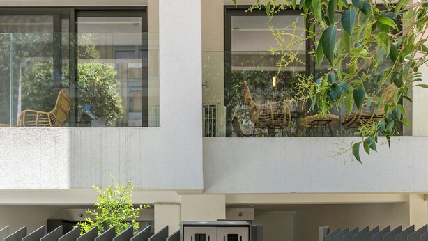 A modern building with a gated entrance, a small outdoor seating area, and a visible elevator. - Cubes Living Athens, Studio 302 (Athina)