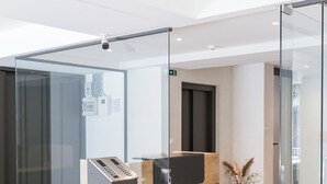 A modern reception desk with glass partitions, a digital keycard reader, and a potted plant. - Cubes Living Athens, Studio 302 (Athina)