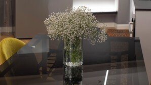 A modern kitchen with a built-in refrigerator, a white shelf with decorative items, and a vase with flowers on the dining table. - New apartment in the historic center of Naples, for families or couples.  (Napoli)
