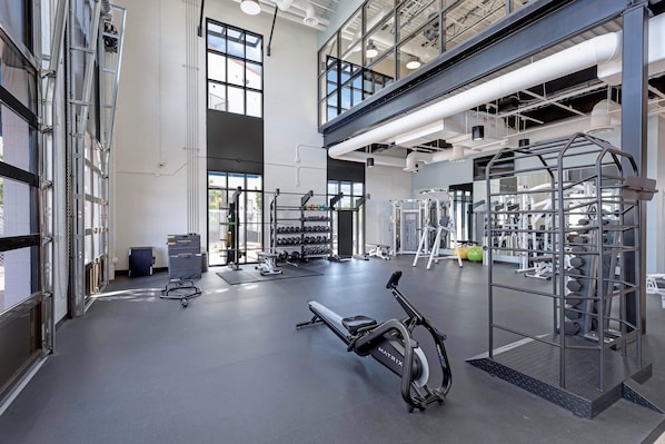 A spacious gym with various exercise equipment, including a treadmill, weight machines, and a squat rack.