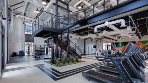 Une salle de sport moderne équipée de tapis de course, d’un escalier et d’une grande fenêtre.