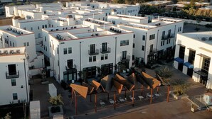 Un bâtiment moderne à plusieurs étages, doté d’espaces extérieurs aménagés pour s’asseoir et d’une cour intérieure.