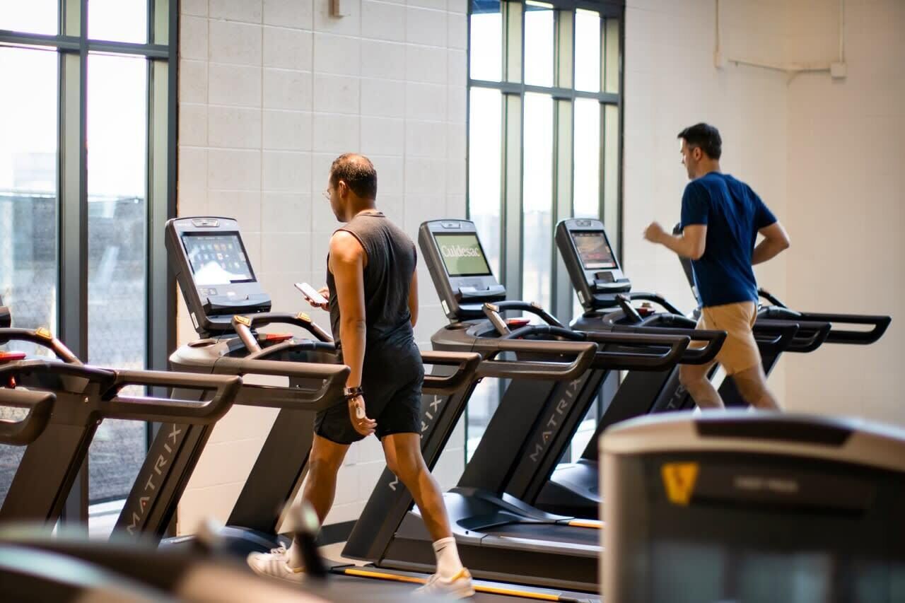 Une salle de sport avec des tapis de course, et une personne qui marche sur l'un d'eux.