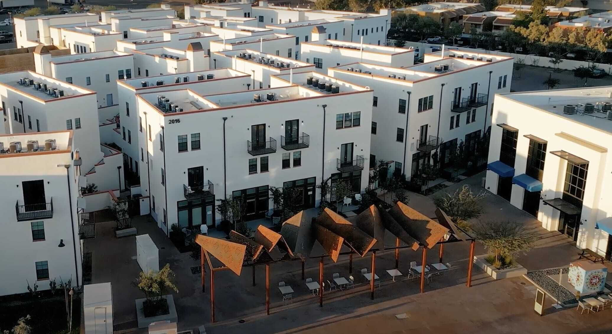 Um edifício moderno com vários andares, áreas de estar ao ar livre e um pátio.