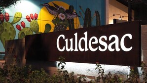 A sign for 'Culdesac' with a colorful mural in the background.