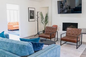 Una sala de estar moderna con un sofá azul, dos sillones de cuero, una mesita de centro y una chimenea.