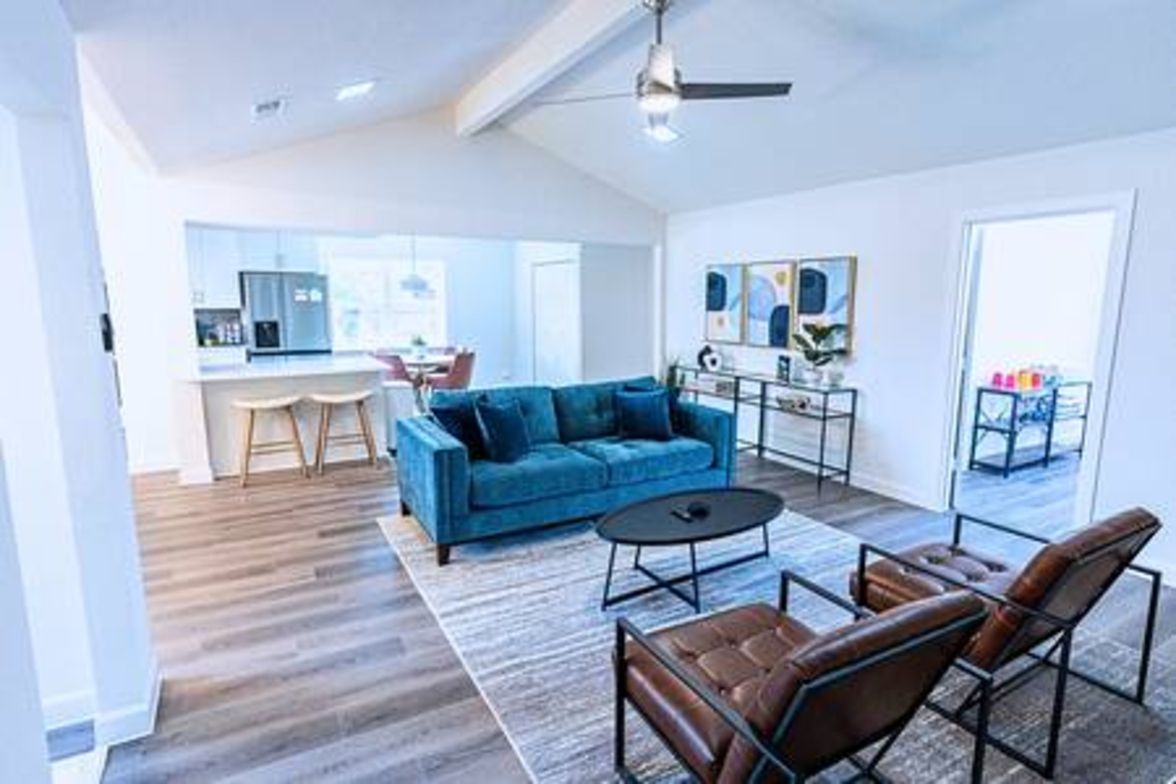 A modern living room with a blue sofa, a coffee table, and leather chairs.