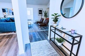 Un salon moderne avec un canapé bleu, une table basse et une console en verre agrémentée d’un miroir.