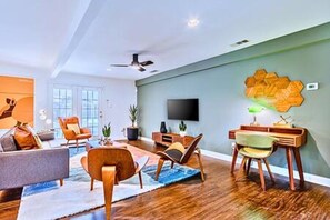 Una sala de estar moderna con una televisión de pantalla plana, muebles de madera y una original pieza de arte mural hexagonal.
