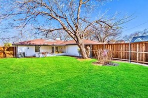 A residential property with a fenced backyard, a detached garage, and a house with a red roof.
