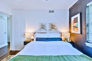 Un dormitorio con cama, mesitas de noche, una puerta y adornos en la pared.