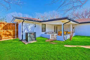 A residential house with a covered patio, a lawn, and a wooden fence.