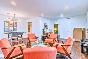 A living room with a pool table, orange chairs, and a chandelier. - Location + Monthly + WiFi + Desk + Pet (Grand Prairie)