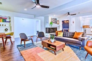 Una sala de estar moderna con sofá, mesa de centro y sillas. Hay una estantería y una chimenea.