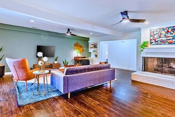 Una sala de estar moderna con sofá, sillón y mesa de centro, chimenea y televisor de pantalla plana montado en la pared.