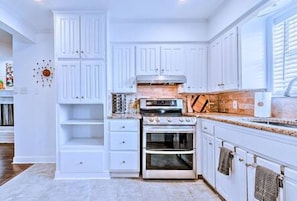 A kitchen with white cabinetry, a stove, and an oven. - Location + Monthly + WiFi + Desk + Pet (Grand Prairie)