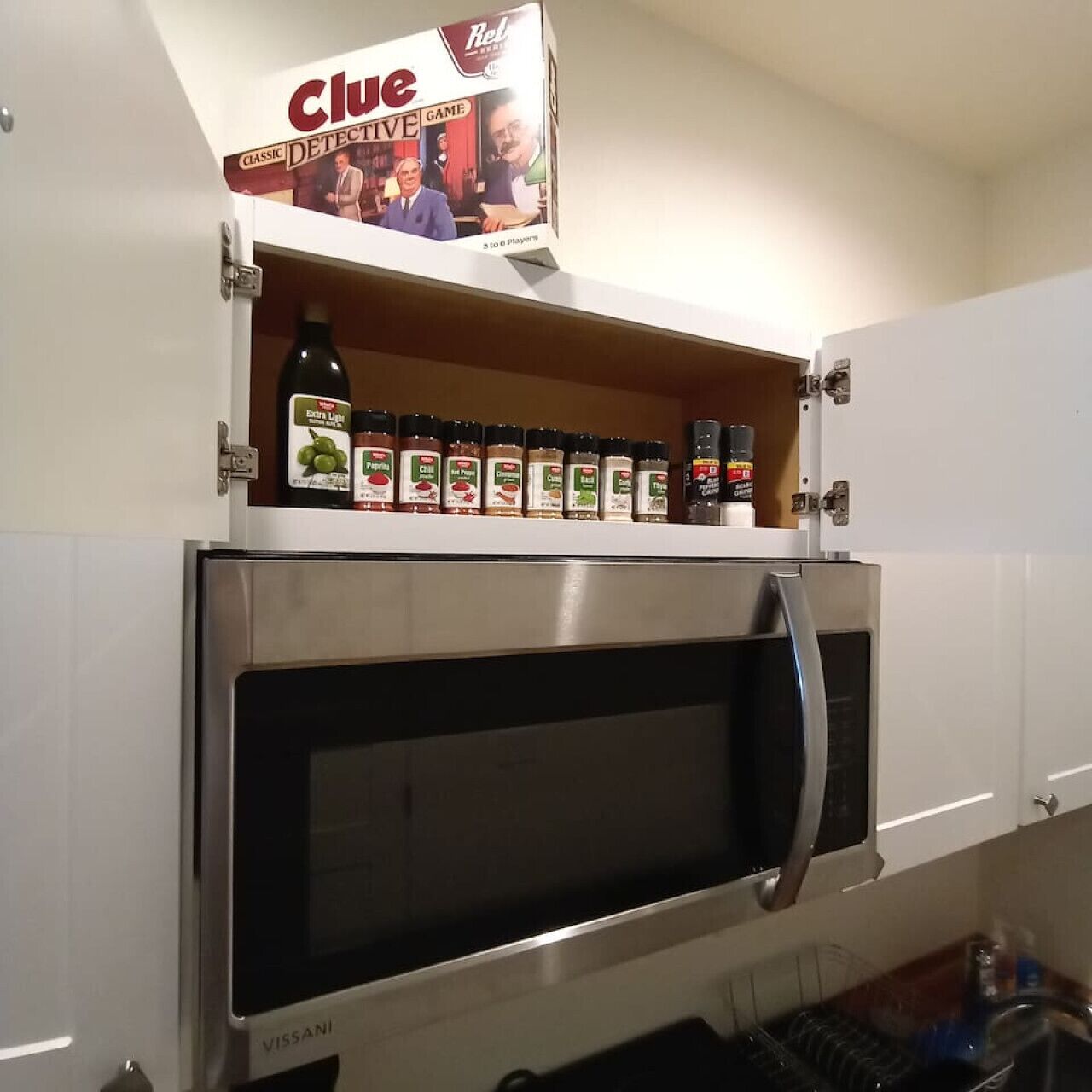 Een keuken met een ingebouwde magnetron en een rek voor kruiden erboven.