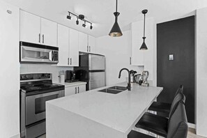A modern kitchen with stainless steel appliances, a central island, and pendant lighting. - Modern & Comfy in Downtown ~ Views ~ Pool (Vancouver)