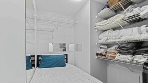 A hotel room with a bed, a mirror, a shelf with folded towels, and a radiator. - Modern & Comfy in Downtown ~ Views ~ Pool (Vancouver)