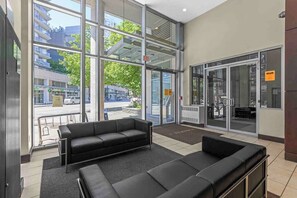 A modern lobby with a black leather sofa, large glass doors, and a view of the street. - Modern & Comfy in Downtown ~ Views ~ Pool (Vancouver)