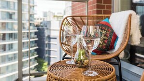 A wicker chair with a cushion and a glass table with two wine glasses and a small plant. - Modern & Comfy in Downtown ~ Views ~ Pool (Vancouver)