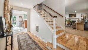 Un vaste espace de vie agrémenté d’un escalier en bois, un coin repas avec des tabourets de bar et un coin salon confortable avec une cheminée.