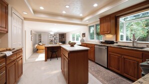 Une cuisine moderne avec des meubles en bois, un îlot central et une grande fenêtre offrant une vue sur l’extérieur.