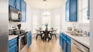 A modern kitchen with blue cabinets, a central island, and a dining table. - Super Clean/ Fun Environment! Low Cleaning Fee! (Georgetown)