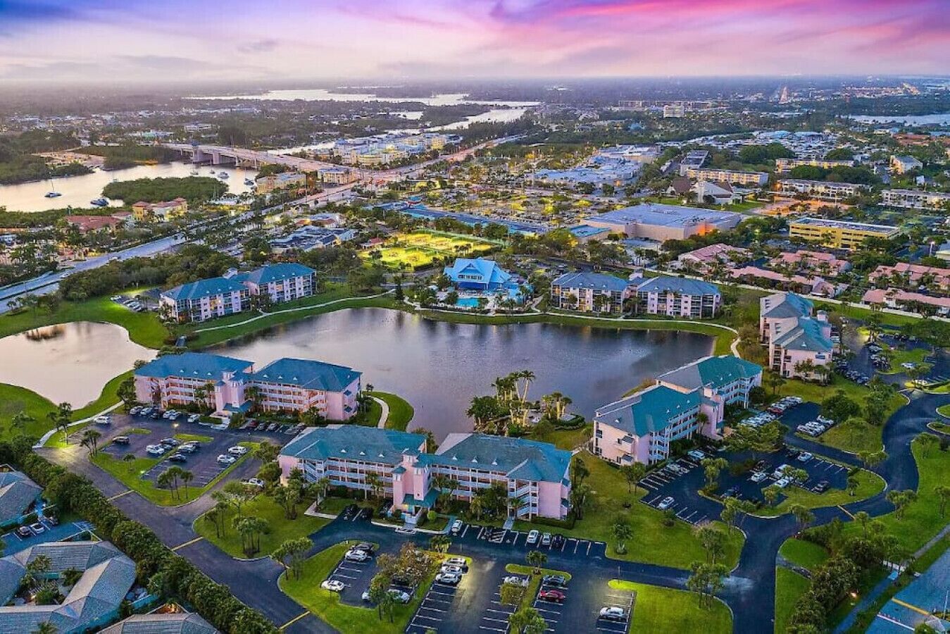 An aerial view of a resort with multiple buildings, a central lake, and surrounding greenery.