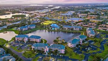 An aerial view of a resort with multiple buildings, a central lake, and surrounding greenery.