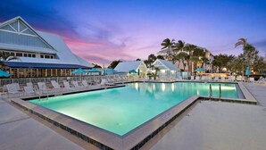 A swimming pool with lounge chairs and umbrellas, surrounded by buildings and palm trees. - Sunrise & Sunset views, Pool, 1/2 mile to beach! (Jupiter)