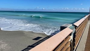 Ein Strand mit einer Holzstege zum Wasser.
