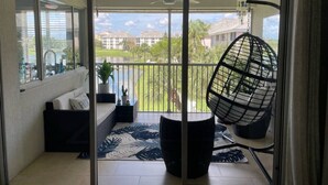 Ein Balkon mit einer Couch, einem Hängesessel und Blick auf eine Wohngegend.