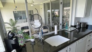 Eine moderne Küche mit schwarzem Arbeitsplatz, weißen Schränken, einer großen Spüle und einer Kaffeemaschine.