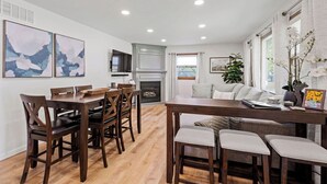 A modern kitchen with a dining area, wooden furniture, and a fireplace. - Fire Pit, Fully Stocked, Family-Friendly Oasis (Wichita)