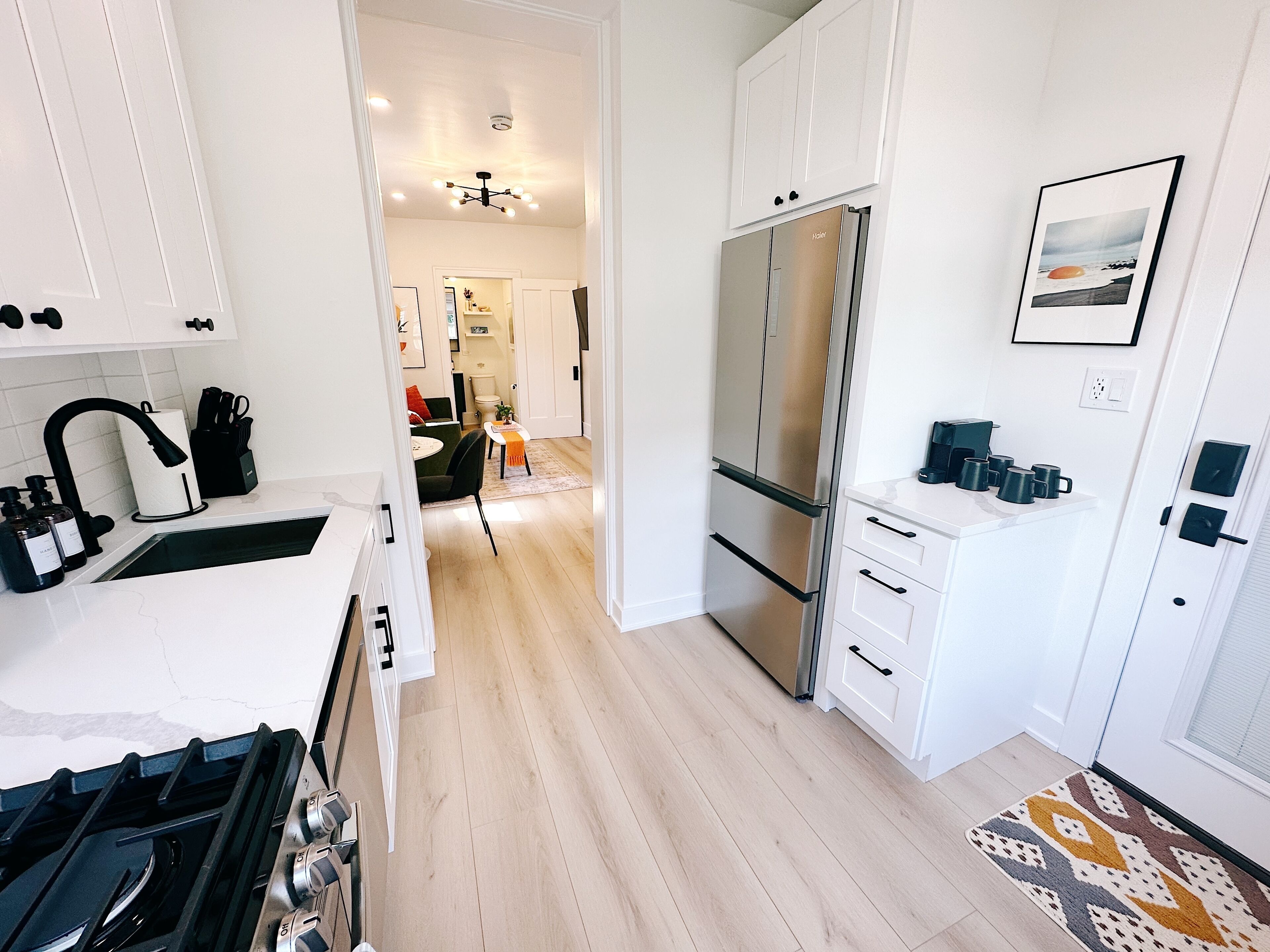 A modern kitchen with white cabinetry, a stainless steel refrigerator, and a gas stove.