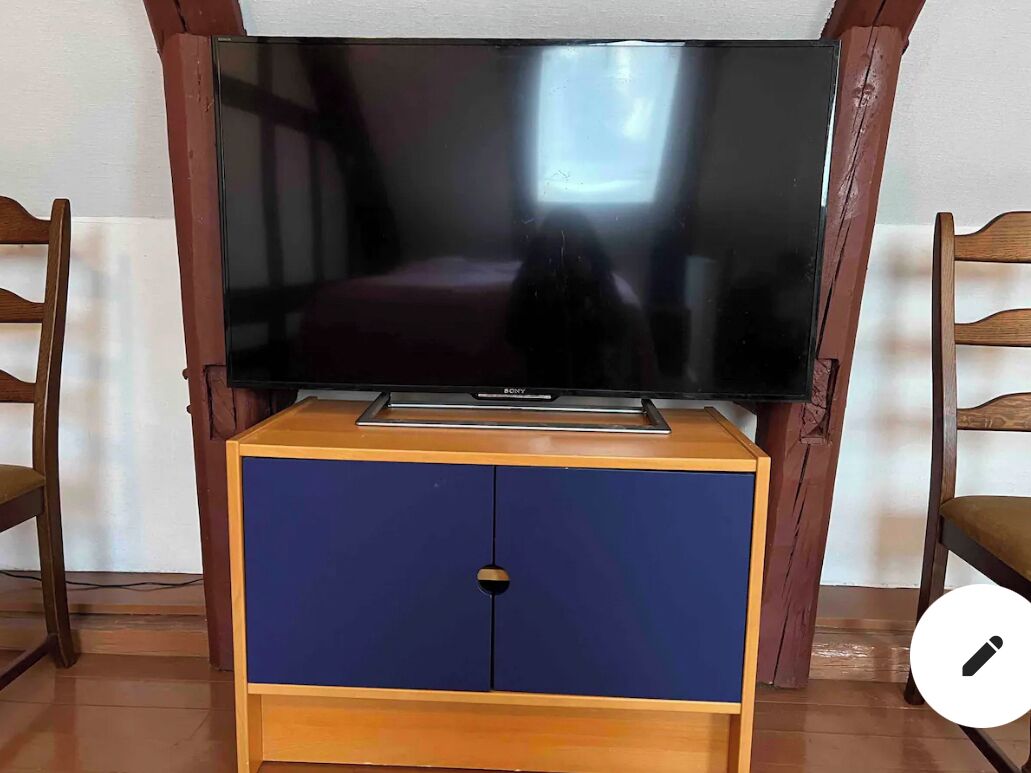 Un televisor de pantalla plana sobre un mueble de madera con un aparador azul debajo.