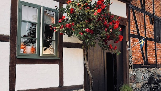 Un bâtiment traditionnel à colombages, avec des fondations en pierre, un toit en tuiles et une fenêtre dotée d’un cadre vert.