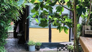 Une cour avec un chemin en pierre, un banc en bois et des plantes en pot.