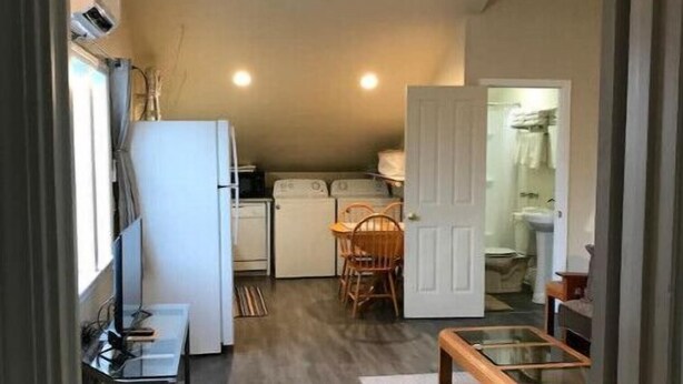 A compact kitchen with a refrigerator, microwave, and dishwasher. There is a dining area with a table and chairs, and a small seating area with a bench. - 1-bedroom apartment just 6 minutes drive to Lithia & Driveway Fields (Medford)