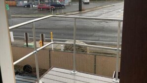 A view from a balcony overlooking a street with a gas station and parked cars. - 1-bedroom apartment just 6 minutes drive to Lithia & Driveway Fields (Medford)
