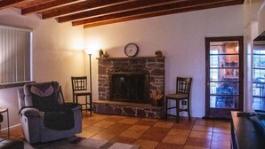 Una sala de estar acogedora con chimenea de piedra, vigas de madera y un espacio de estar cómodo.