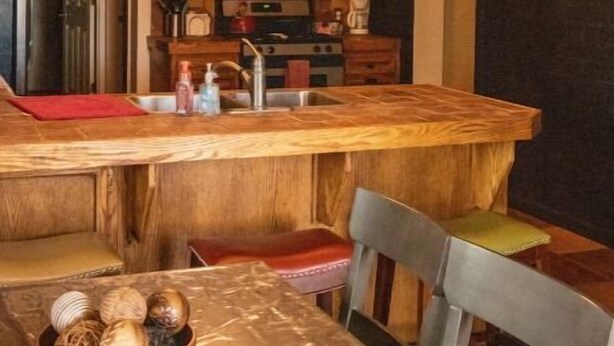Una cocina con armarios de madera, una isla central y una araña.