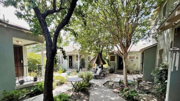 Une cour intérieure avec un chemin central, bordée de verdure et dotée d’espaces pour s’asseoir à l’extérieur.