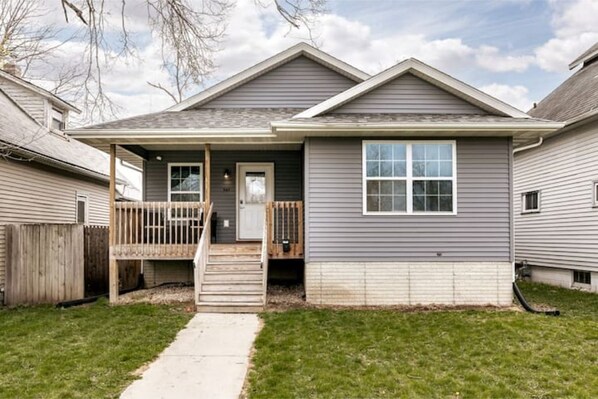 A two-story house with a front porch, a small front yard, and a visible door. - Stadium House - Next to Kernels/Roughriders Arena (Cedar Rapids)